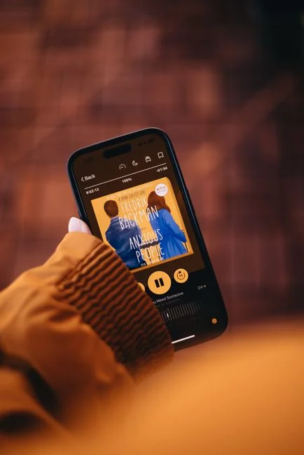 Person holding a smartphone displaying a music app login screen in focus.